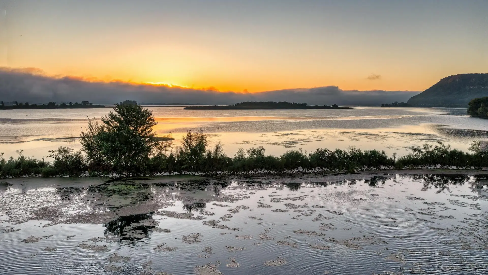 Sunrise over a wide flat lake with morning mist, the calm before a carp fishing tournament at Utah Lake